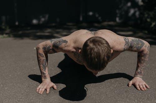 Free A Shirtless Tattooed Man Doing Push Ups on the Concrete Floor Stock Photo