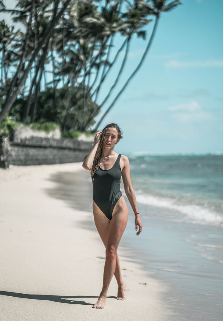 Confident Young Woman In Swimwear Walking Along Sandy Seashore In Tropical Country