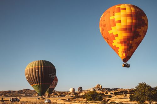 Free Vibrant hot air balloons floating over picturesque countryside with a clear blue sky. Stock Photo