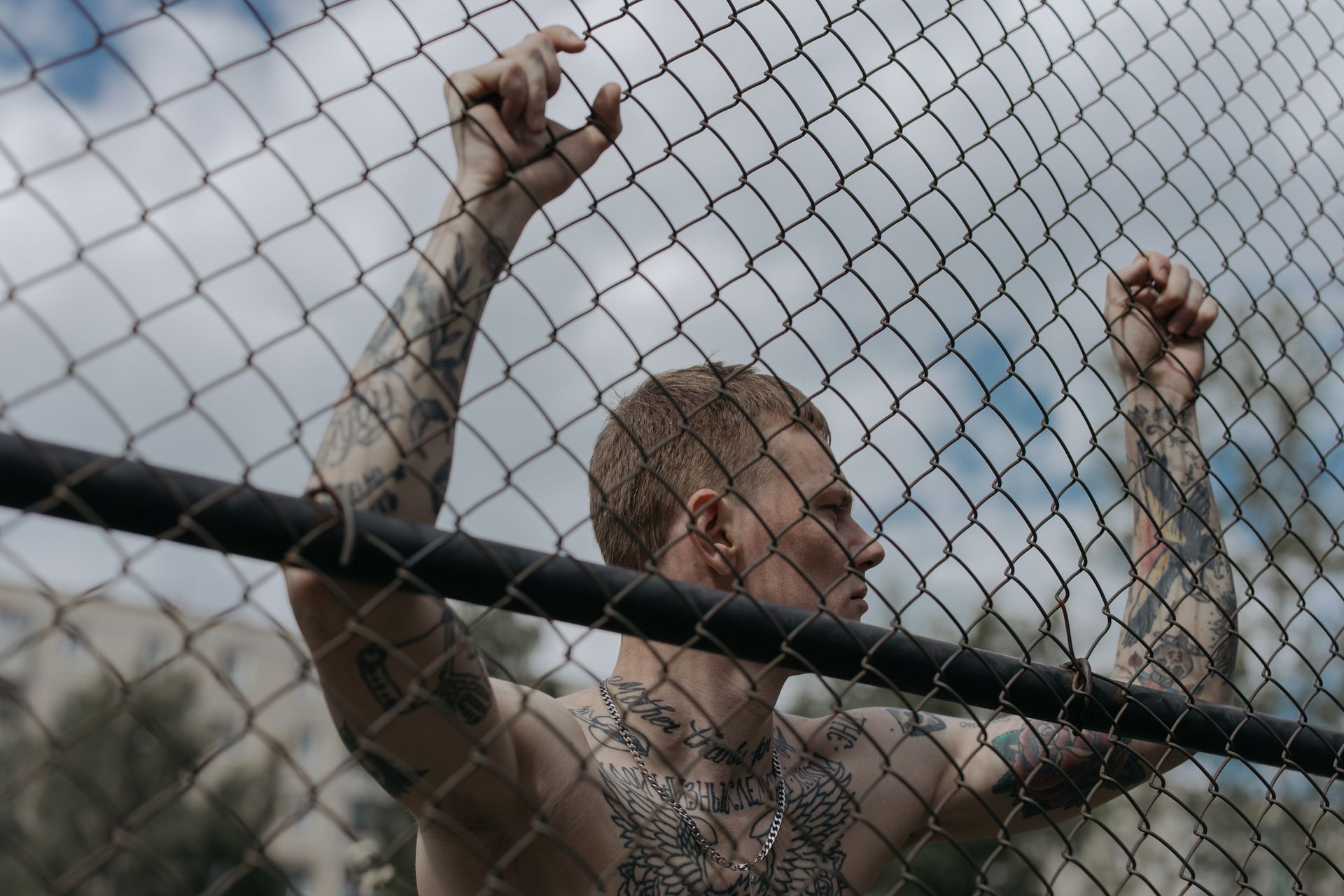 Low Angle Shot of Man Holding on Wire Mesh