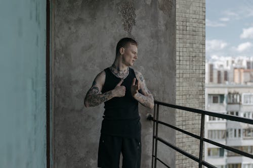 Man in Black Tank Top Standing Near Metal Railing while Looking Afar