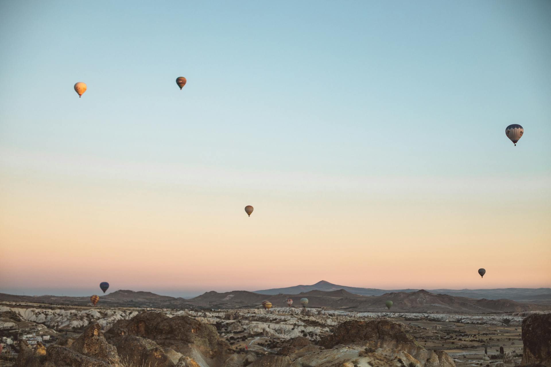 Colorful hot air balloons soar over Cappadocia's unique landscape at sunrise, creating a magical scene.