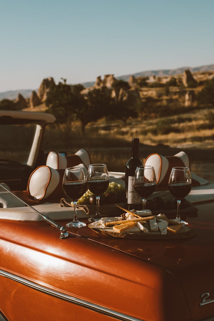 Wine Bottle And Glasses On The Trunk Of A Red Car