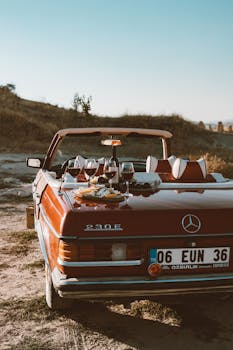 A scenic outdoor picnic setup on a vintage convertible car featuring wine and snacks.