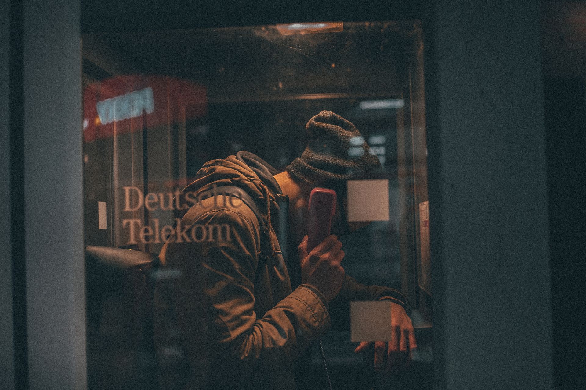 Young man talking on telephone in public call box