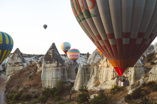Free Colorful hot air balloons soaring over the stunning rock formations of Cappadocia, Turkey. Stock Photo