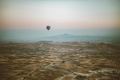 Hot Air Balloon Flying Over Mountain Area at Sunset 