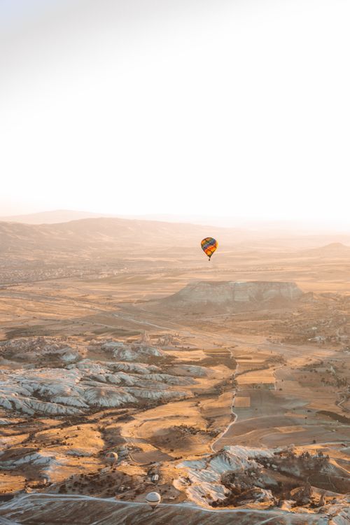 Free A breathtaking view of a hot air balloon drifting over a Turkish landscape at sunset, showcasing natural beauty. Stock Photo