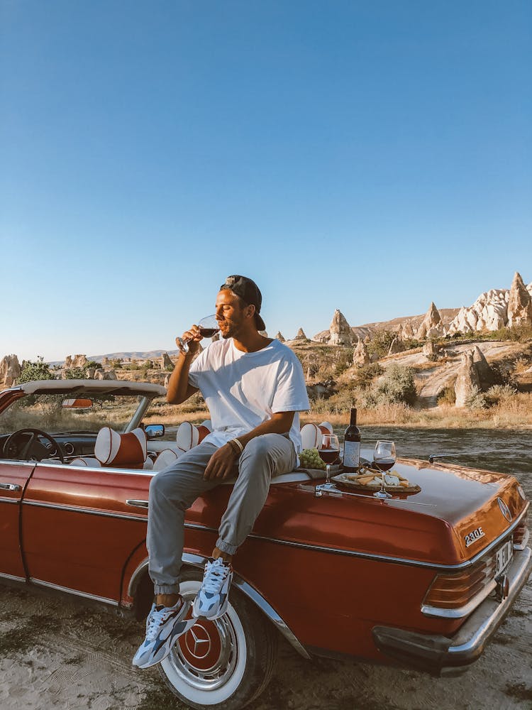 Man Sitting On A Trunk Of A Vintage Mercedes And Drinking Wine 