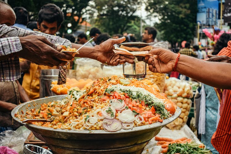 Man Passing Food To Another Person On A Street Food Festival