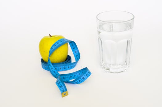 Clear Drinking Glass Near in Blue Tape Measure and Apple Fruit