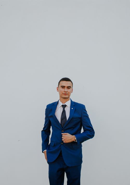 Free Portrait of a confident young man in a stylish blue suit against a minimalist background. Stock Photo