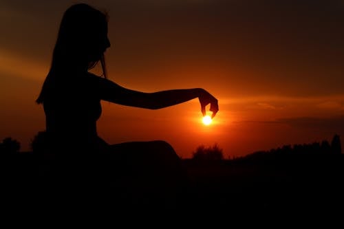 Force Perspective Photography of Woman Picking Sun