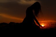 草地上，日落时捕捉到女人艺术剪影的宁静时刻