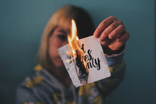 A woman holds a burning paper with text, capturing a moment of transformation and energy.