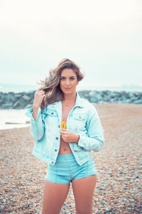 Free Woman in Denim Jacket Standing on the Beach Stock Photo