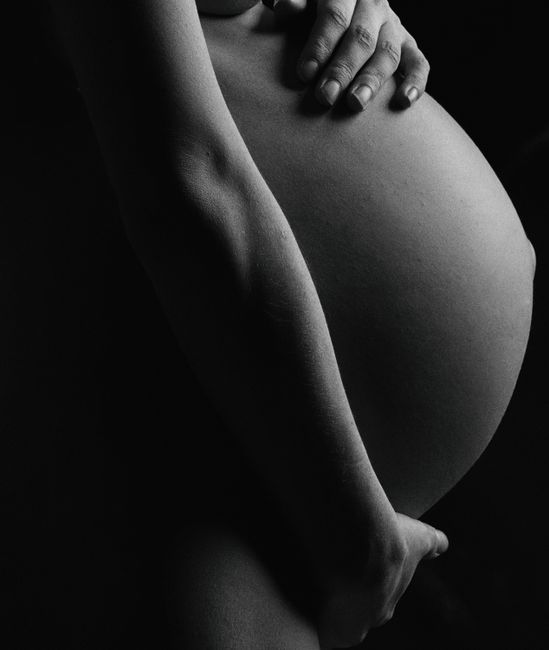 Artistic monochrome close-up of a pregnant woman's belly, showcasing maternal beauty.