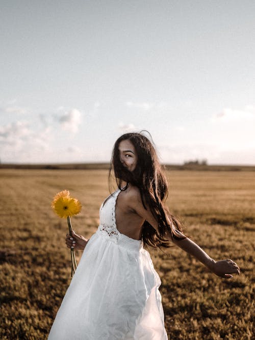 Woman in White Dress Standing on Brown Grass Field