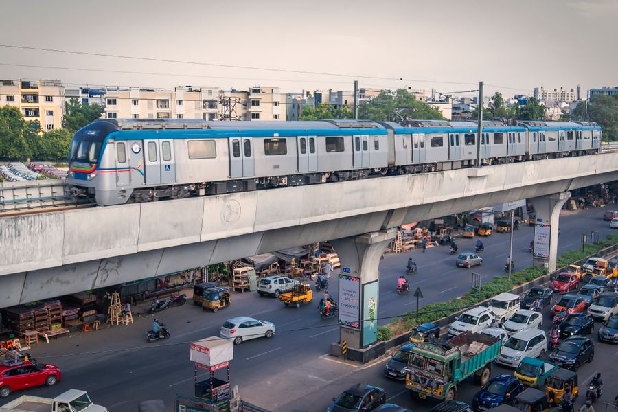 A metro train traverses above city traffic in bustling Hyderabad, India.