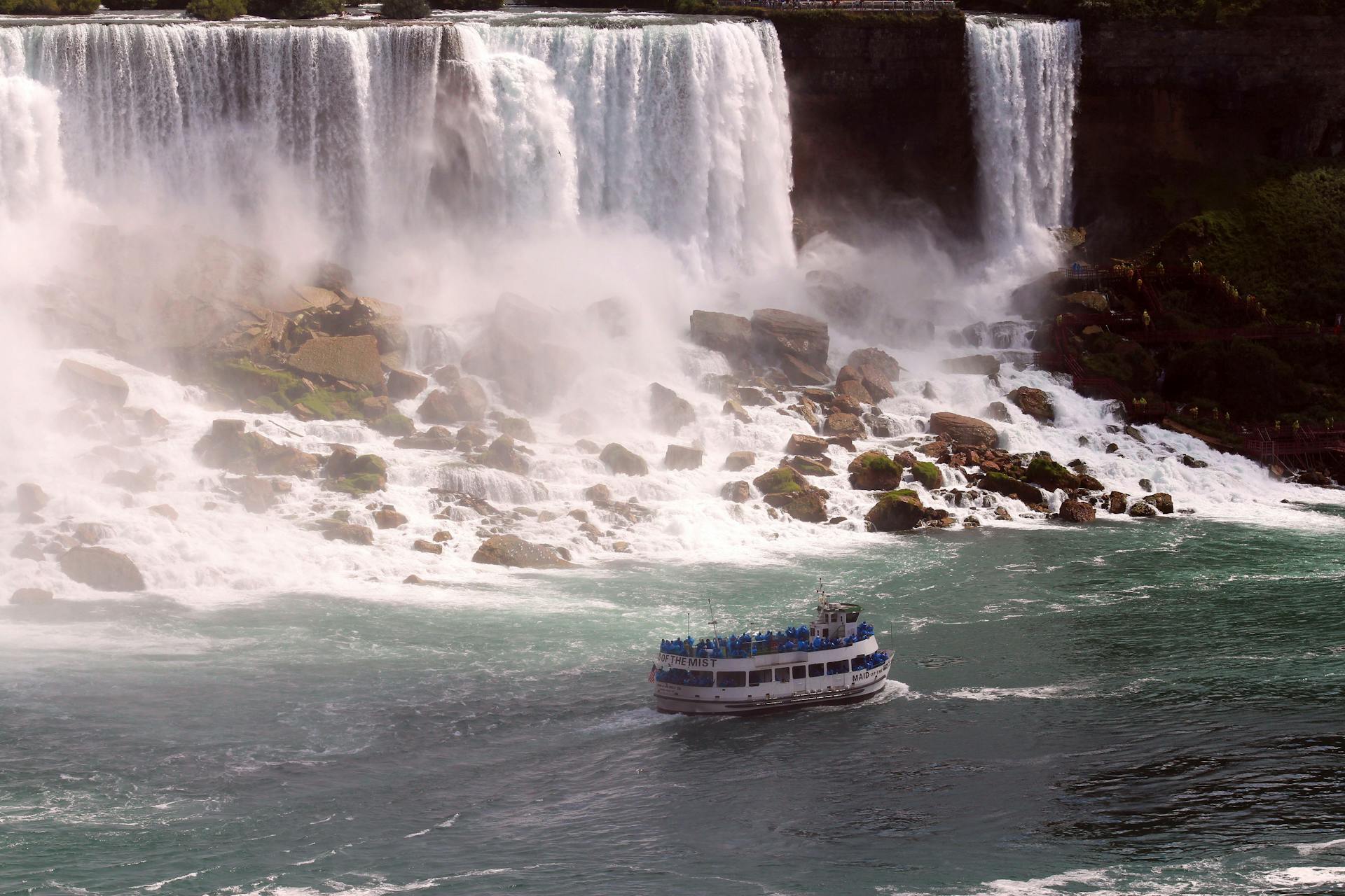 A breathtaking view of Niagara Falls with a ferry boat navigating the misty waters below.