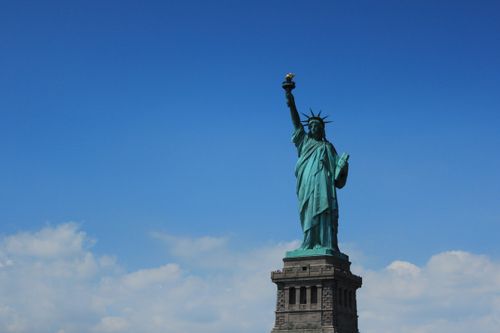 Free The iconic Statue of Liberty stands tall against a vibrant blue sky in New York City. Stock Photo