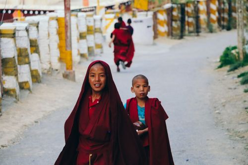 Free Two young Buddhist monks in red robes walking through a Himalayan town in India, capturing local culture and spirituality. Stock Photo