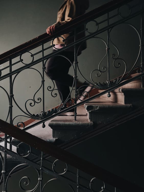 Person Holding on Railing While Going Down The Stairs · Free Stock Photo