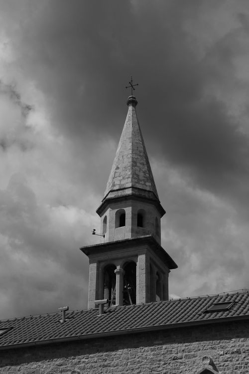 Free Black and white photo of a church tower in Budva against a cloudy sky. Stock Photo