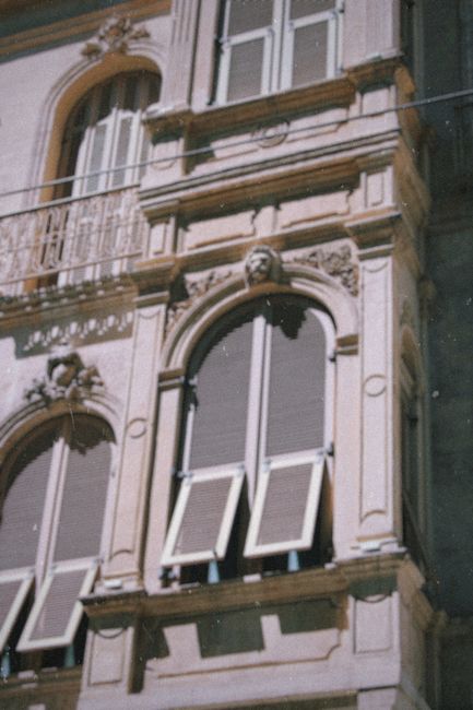 Close-up of a classical building façade featuring arched windows and ornate architectural details.