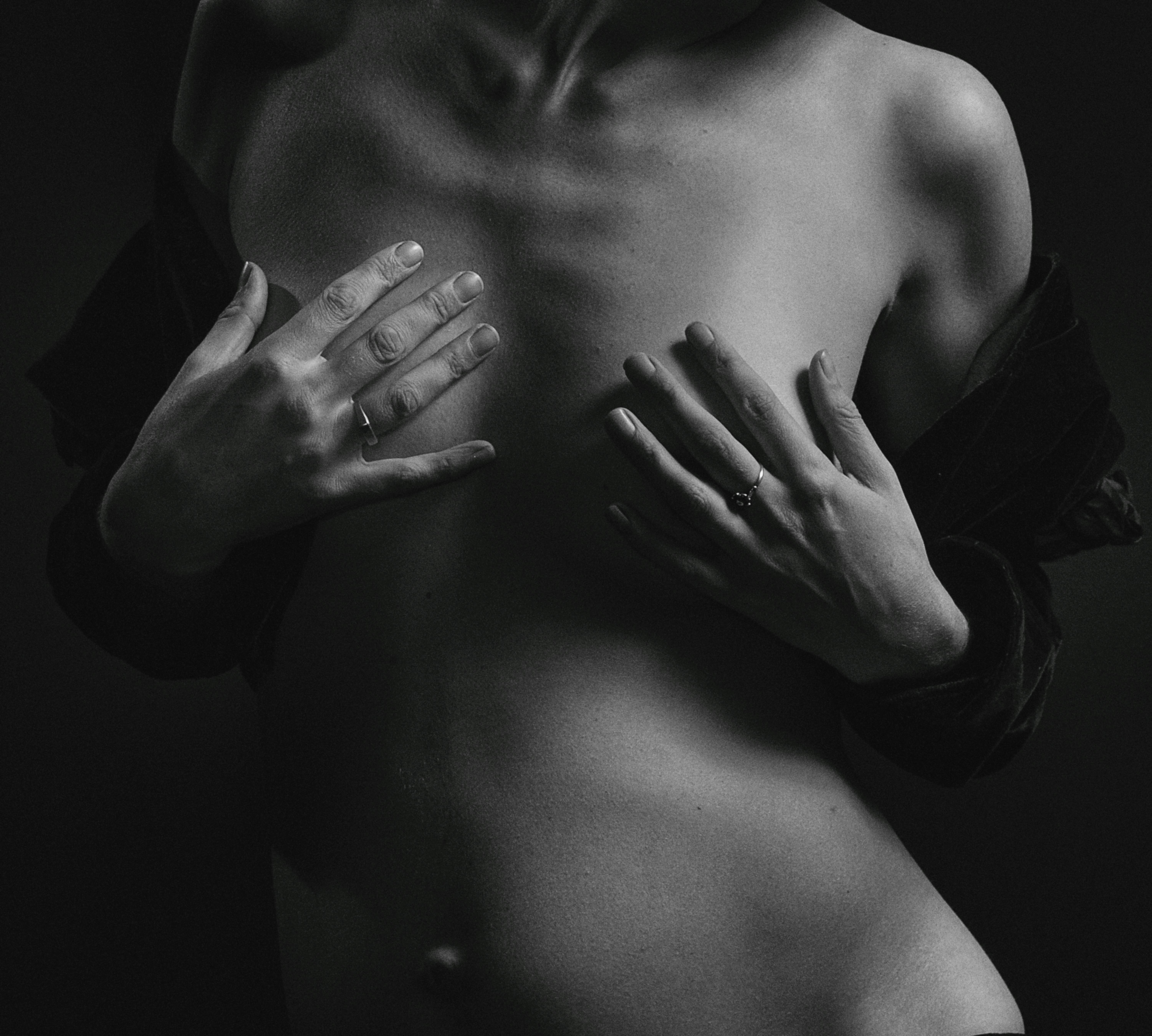 a grayscale photo of a woman covering her breasts using her hands