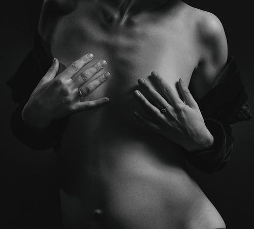 A Grayscale Photo of a Woman Covering Her Breasts Using Her Hands