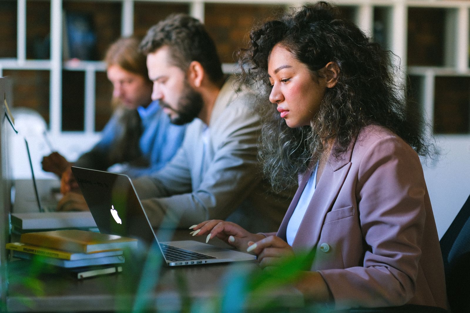 Equipe jovem focada trabalhando em laptops em espaço de coworking moderno