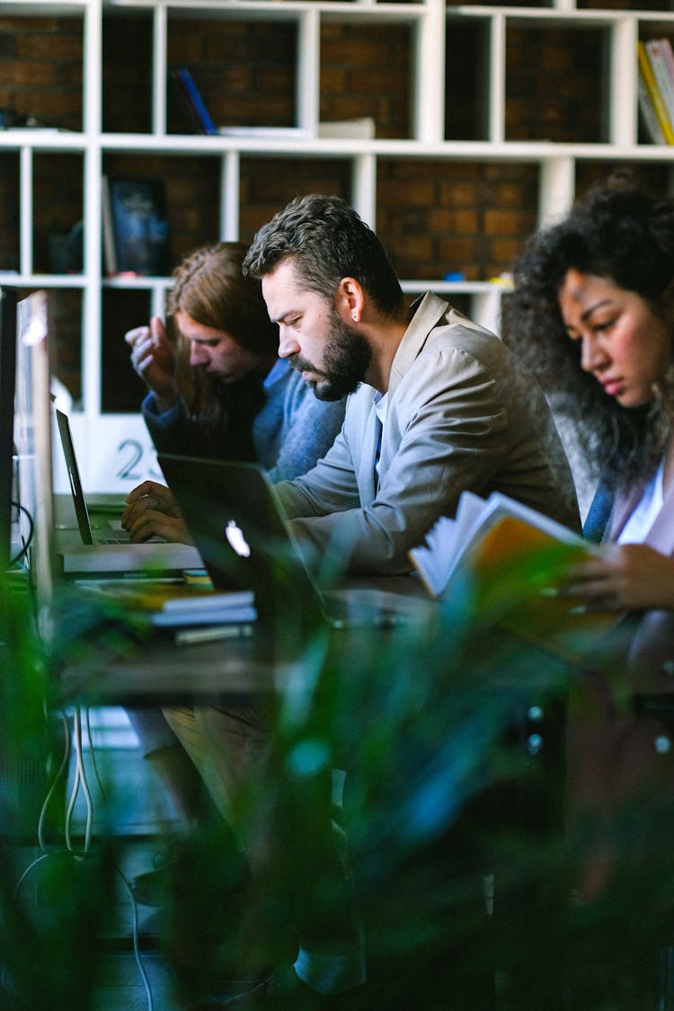 Serious Young Coworkers Working On Laptop In Coworking Space