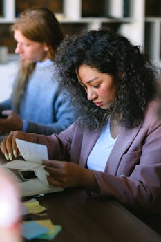Professional woman deeply focused on reviewing paperwork in a modern office setting.