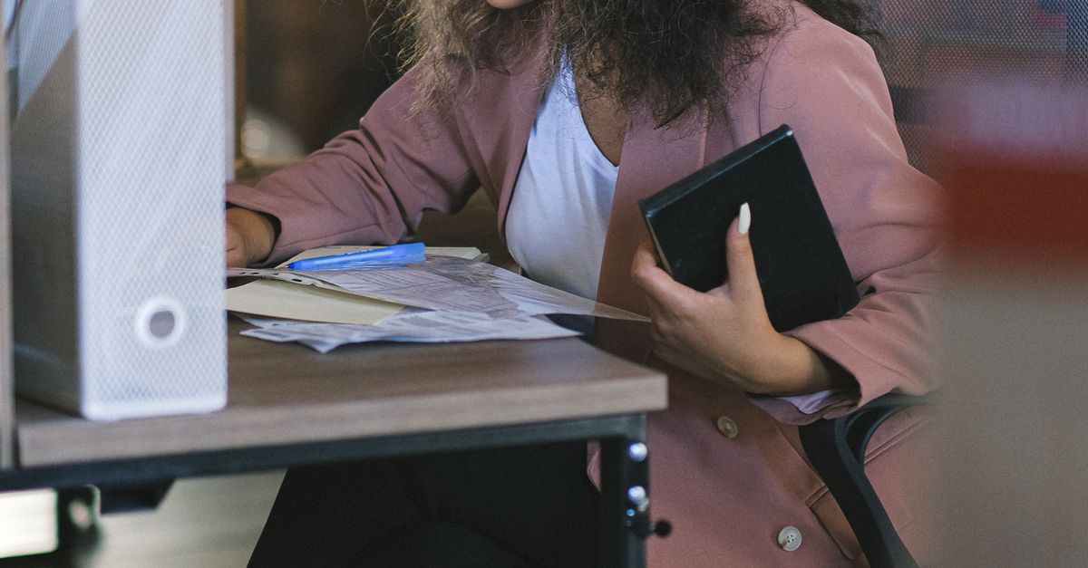 Employee Reading Focused female employee reading documents during work in office · Free ...