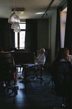 Dimly lit modern office with a team collaborating around desks, ideal for business themes.