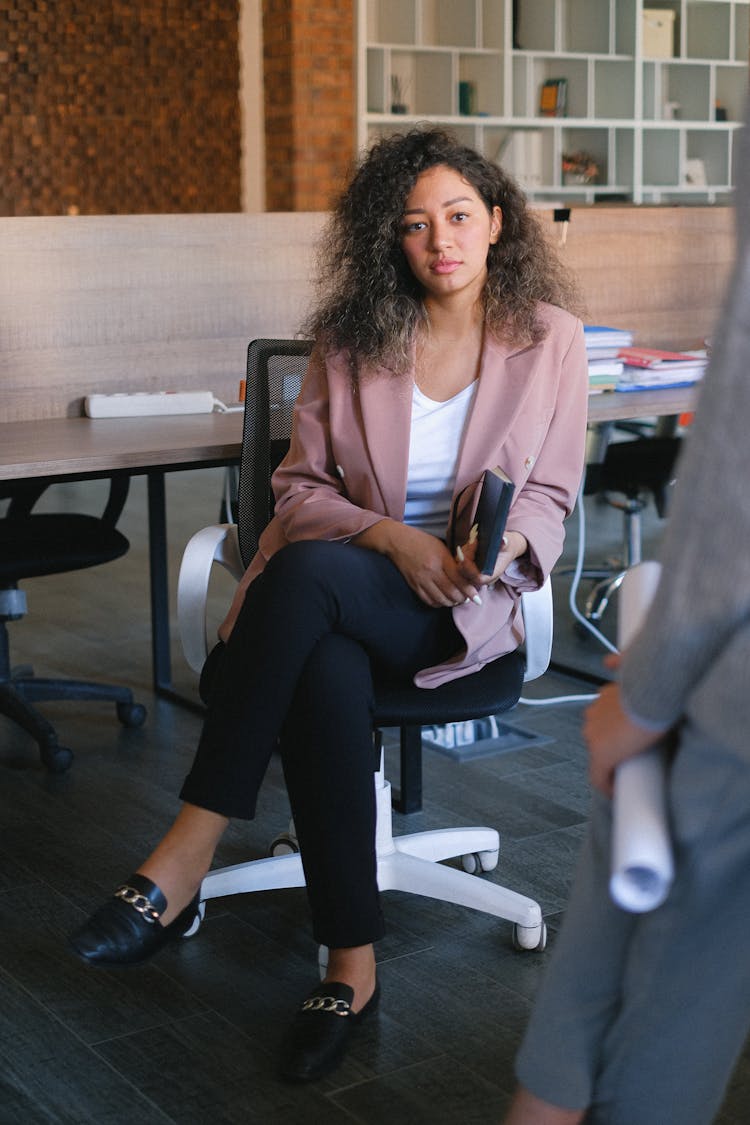 Serious Woman Listening To Colleague In Office