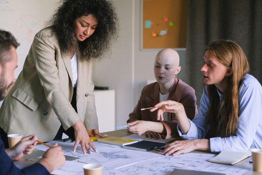 Group of concentrated coworkers working together at table on business strategy with documents during briefing in conference room in office