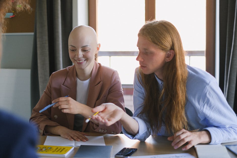 Content bald woman and man with pens working together while sitting at table in modern conference room during meeting in office