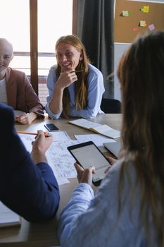 Team members engage in a collaborative meeting, using tablets and papers for planning.