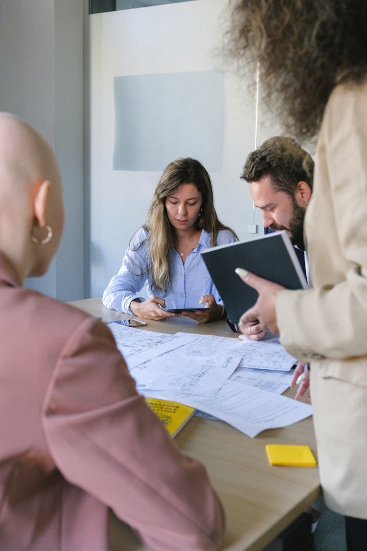 Group Of Colleagues Discussing Work While Using Tablet At Table