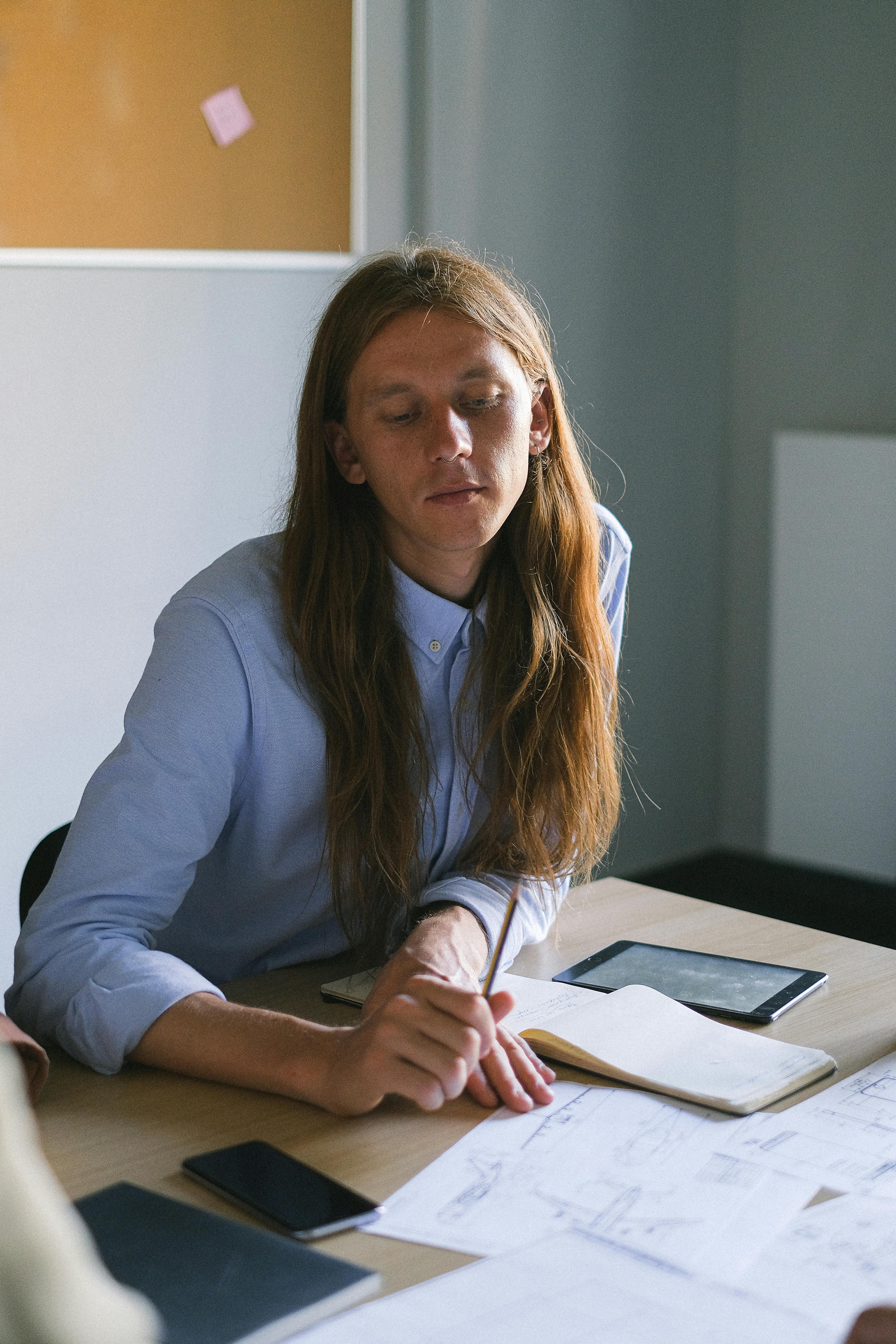 pensive man with long hair working at table