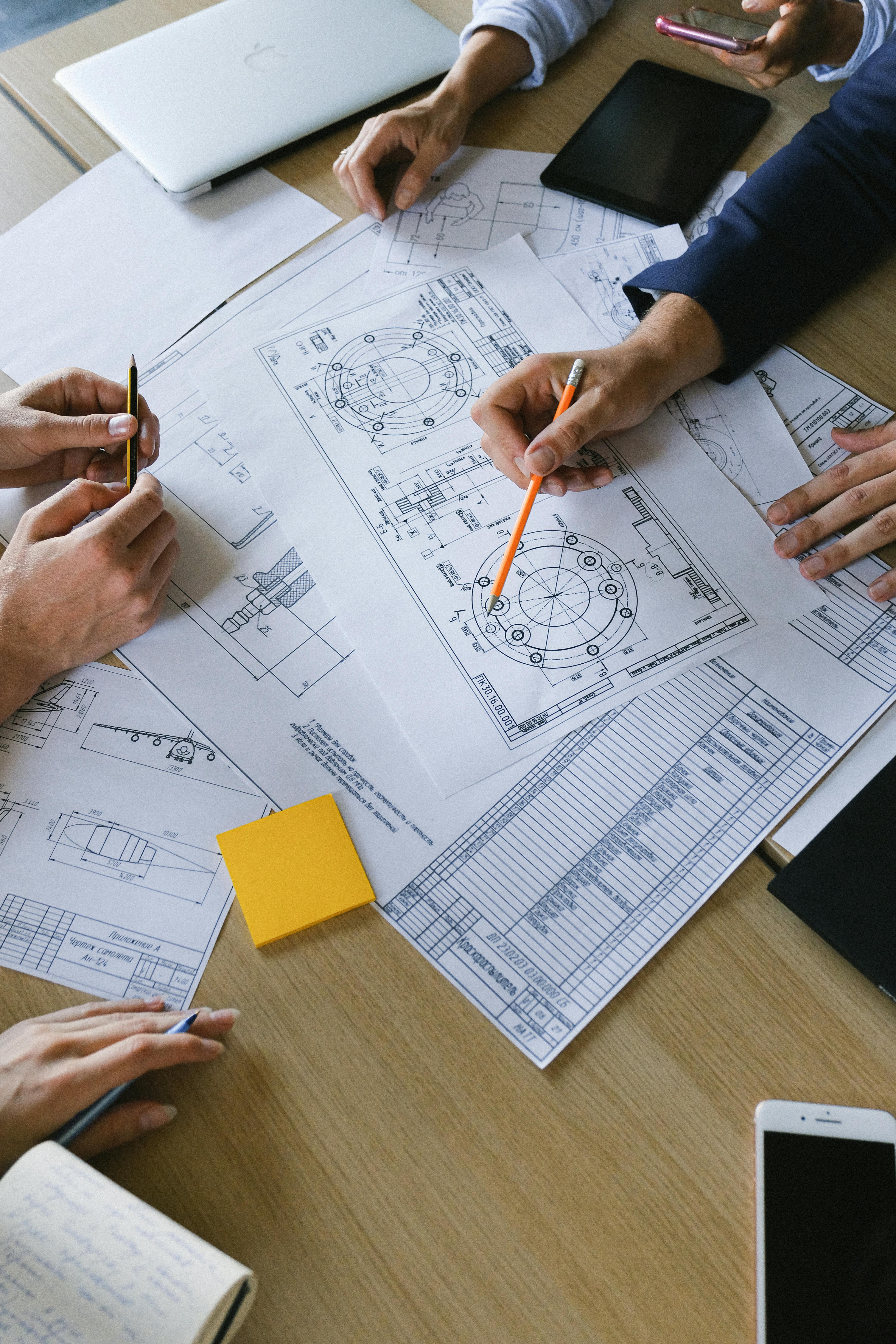 group of colleagues discussing engineering plan on papers at table