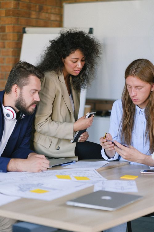 Free Group of diverse men and woman talking and using mobile phone at table with papers and table in office Stock Photo