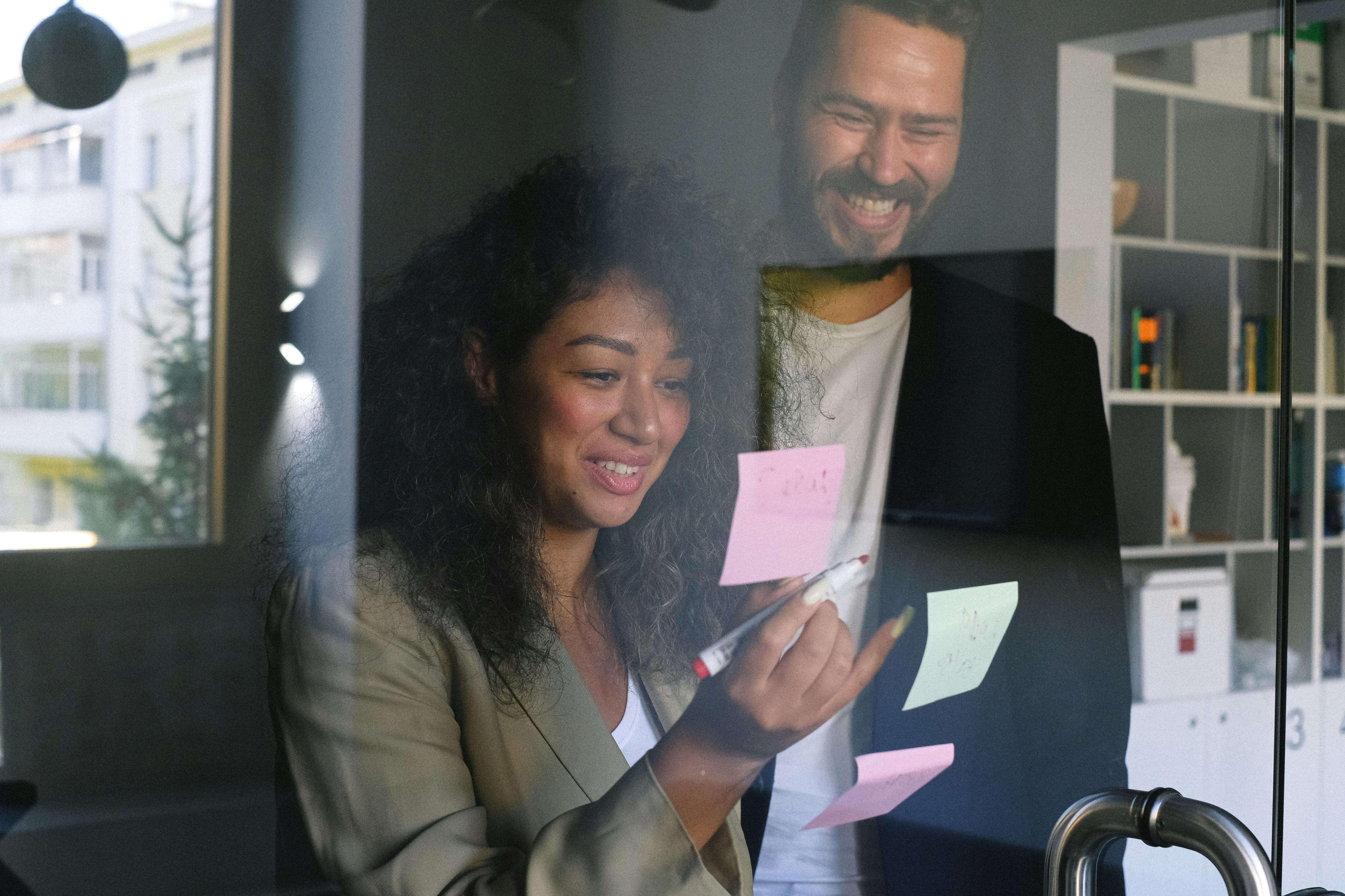 multiethnic cheerful colleagues looking at stickers and smiling