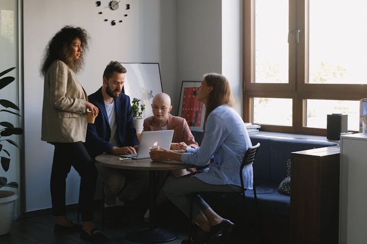 Group Of Diverse Colleagues Using Laptop And Talking In Office