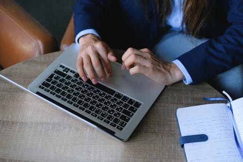 Entrepreneur sitting at table with notebook and using laptop