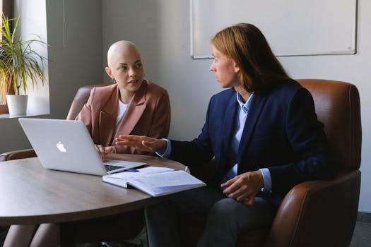 Two professionals engaged in a serious business meeting using a laptop.
