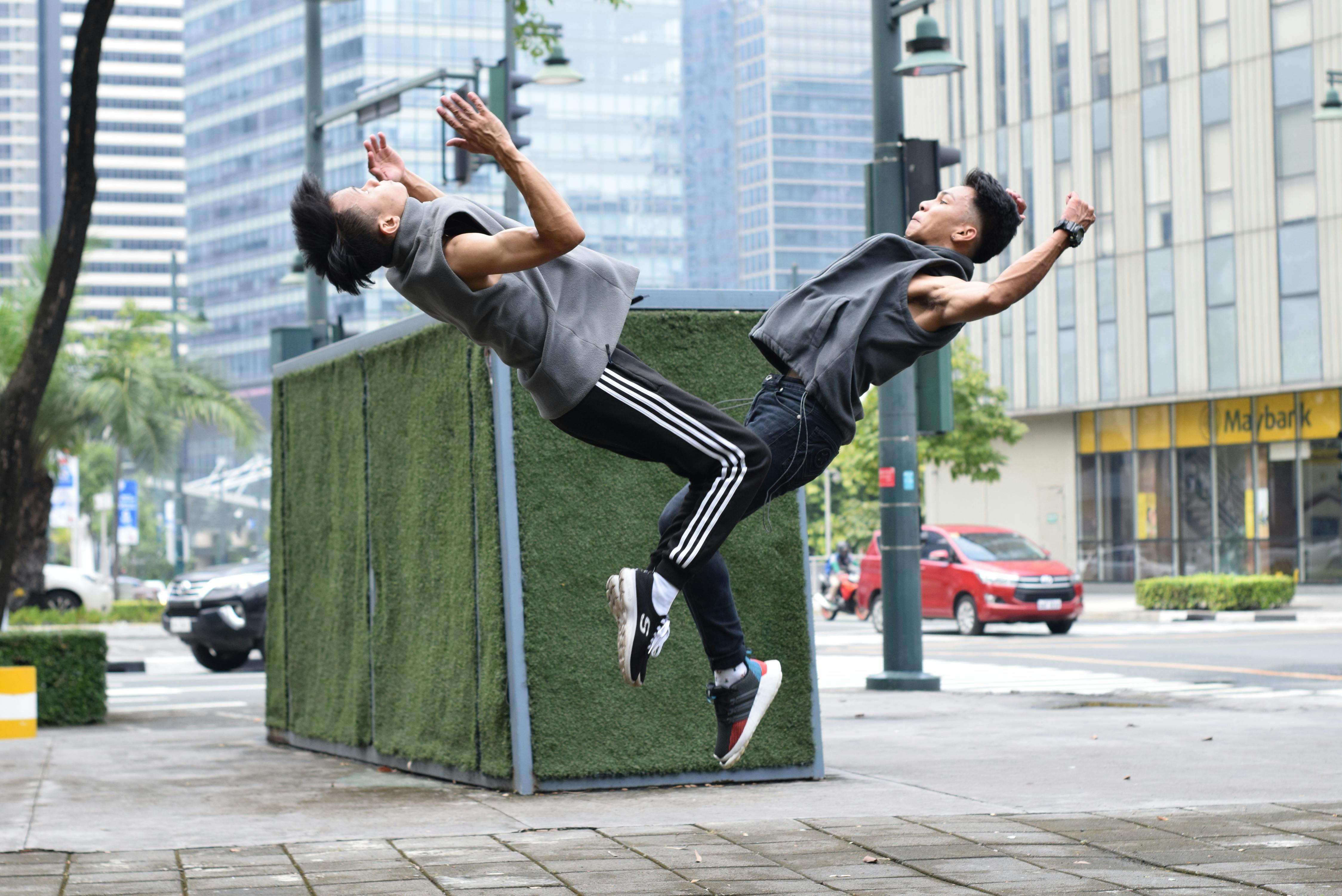 young ethnic male athletes doing backflip on street