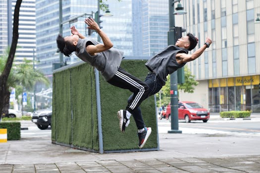 Two young men execute a synchronized backflip outdoors amidst urban architecture.